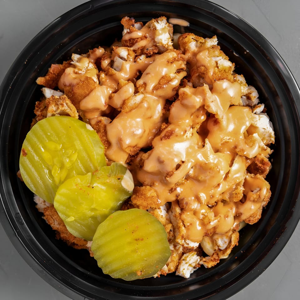 Papi's Hot Chicken bowl with fried chicken pieces, sauce, and pickle slices.