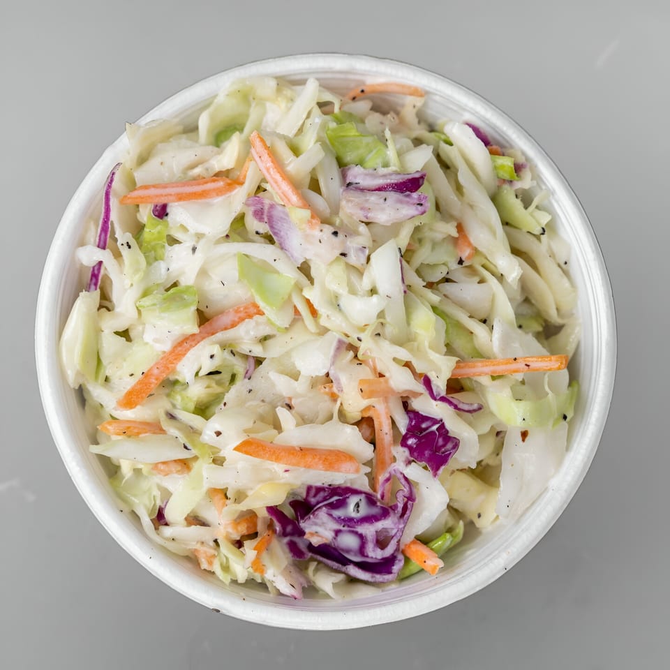 A white bowl filled with Papi's Hot Chicken coleslaw, featuring shredded cabbage, carrots, and purple cabbage.