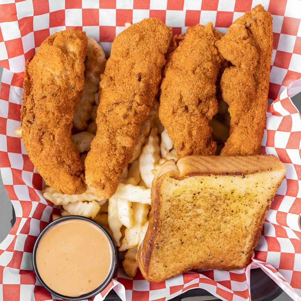 Papi's Hot Chicken tenders, fries, Texas toast, and dipping sauce in a red-checkered basket.